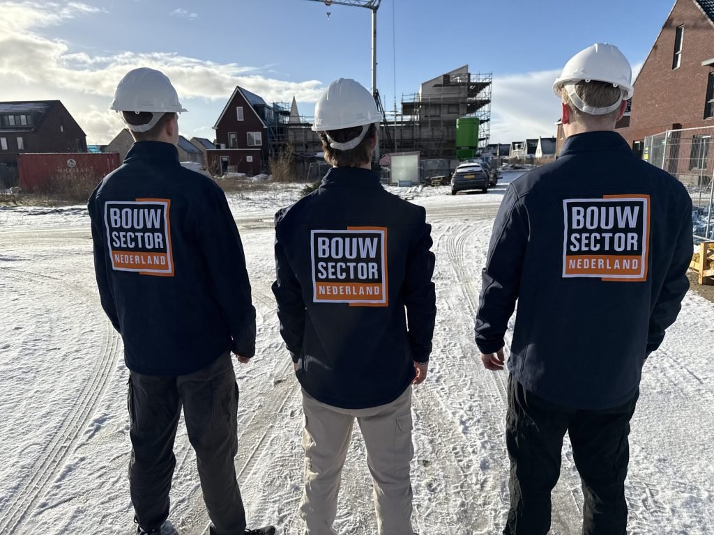 Drie vakmensen van Bouwsector Nederland met helm en bedrijfsjas bij nieuwe woningen in aanbouw